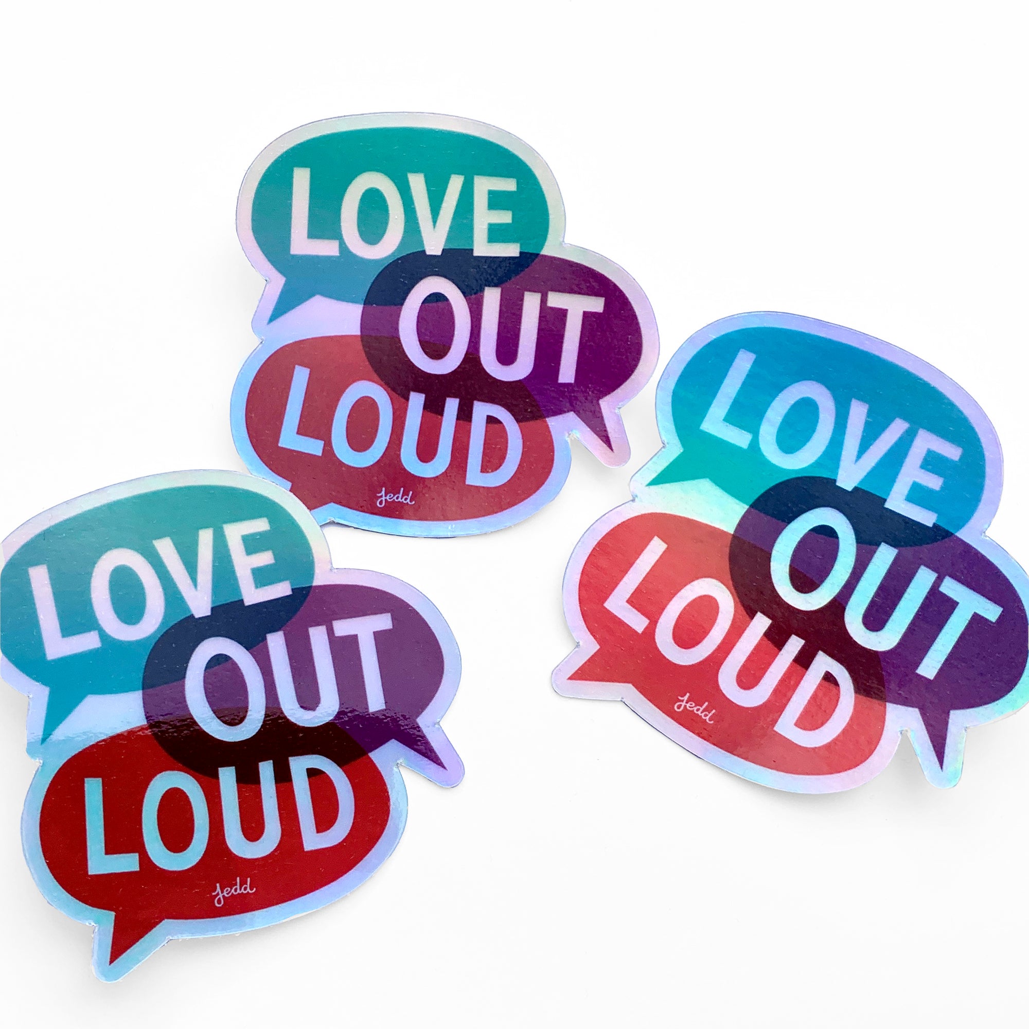 Three holographic stickers with a design that says "Love Out Loud"