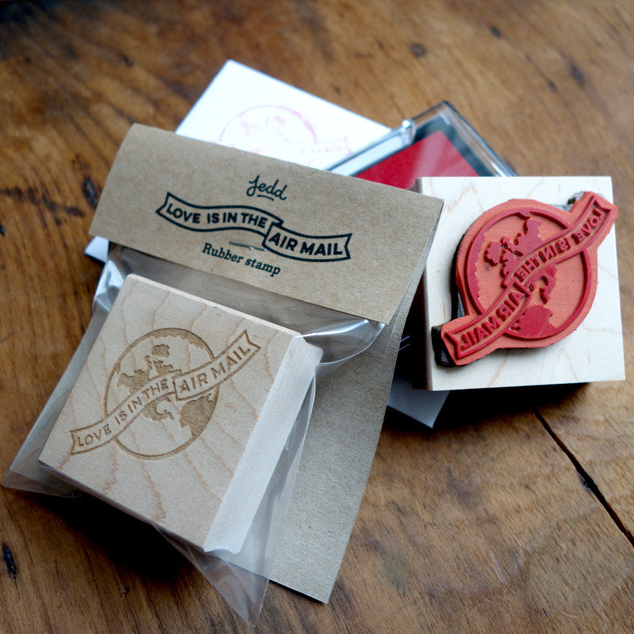 Rubber stamp and packaging, with a globe design that reads "Love is in the Air Mail"