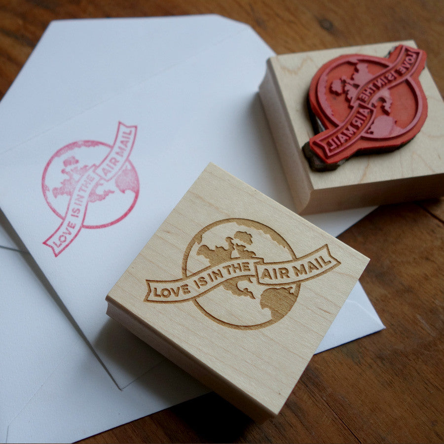 Rubber stamp and envelope, with a globe design that reads "Love is in the Air Mail"